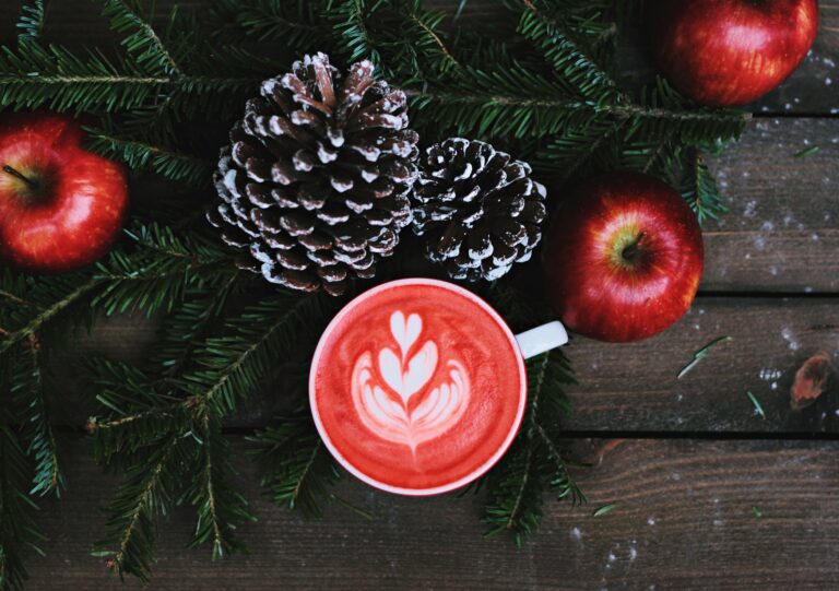 A festive latte next to a Christmas wreath.